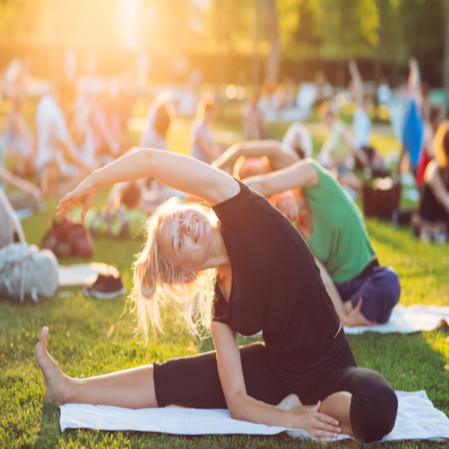 A group of young people do yoga in the Park at sunset.
